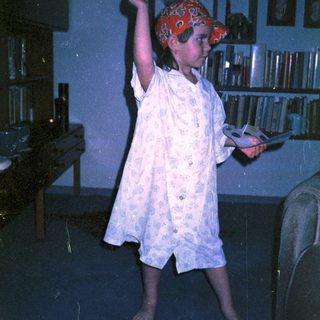 Child in pirate hat playing sword game indoors.