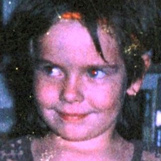 Young girl wearing patterned dress indoors.