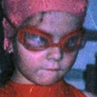 Young child in red swimwear and cap indoors.