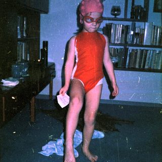 Young child in red swimwear and cap indoors.