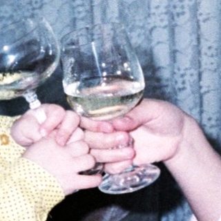 Two children toasting with wine glasses indoors.