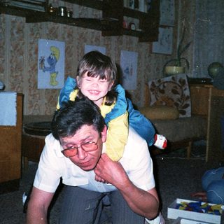 Joyful man carrying smiling child indoors.