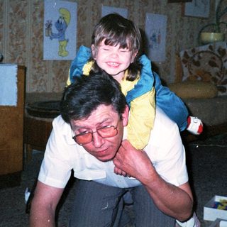 Joyful man carrying smiling child indoors.