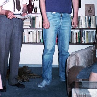 Three people posing indoors with bookshelves in background.