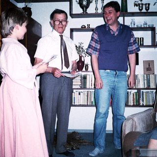 Three people posing indoors with bookshelves in background.