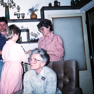 Family gathering indoors during a celebratory handshake moment.