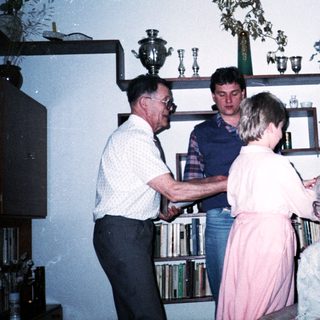 Family gathering indoors during a celebratory handshake moment.