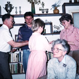Family gathering indoors during a celebratory handshake moment.
