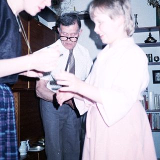 Three people examining a small object indoors.