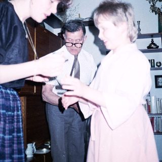 Three people examining a small object indoors.