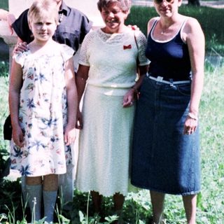 Five women posing outdoors near a statue.