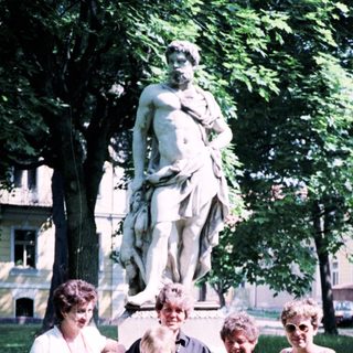 Five women posing outdoors near a statue.