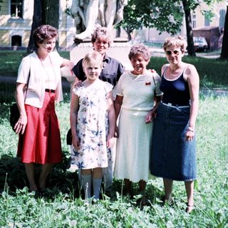 Five women posing outdoors near a statue.
