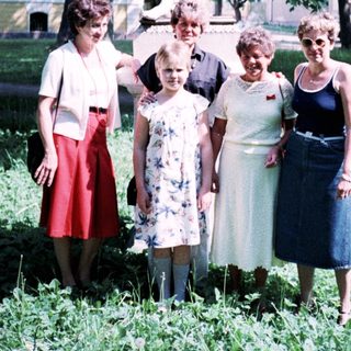 Five women posing outdoors near a statue.