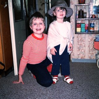 Two children posing indoors, smiling.