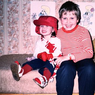 Two children posing happily with Smurf-themed decorations.