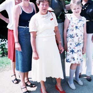 Five women posing together outdoors near statue.