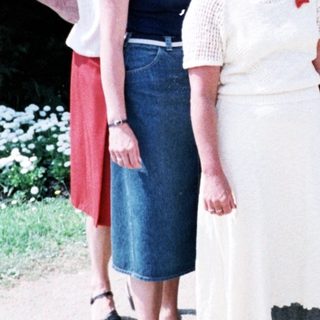 Five women posing together outdoors near statue.