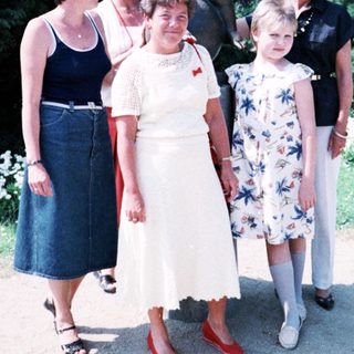 Five women posing together outdoors near statue.