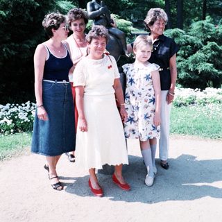 Five women posing together outdoors near statue.