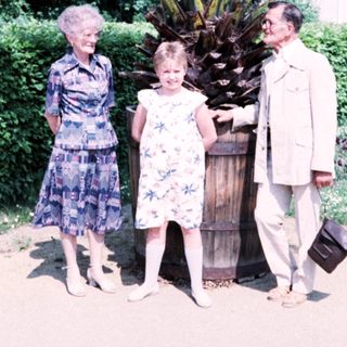 Family posing with large palm plant outdoors.
