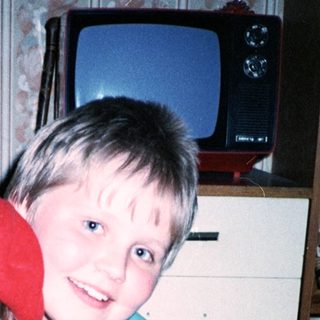 Two children posing indoors, wearing matching red and white outfits.