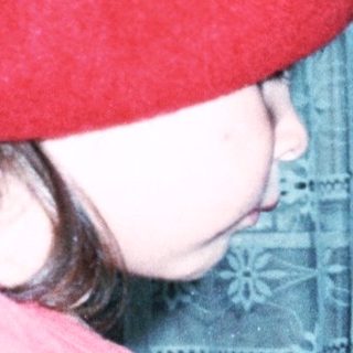 Young girl wearing red beret and shirt playing piano.