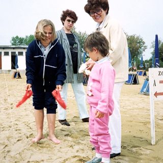 People playing beach flag game with child.
