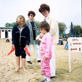 People playing beach flag game with child.