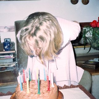 Dog blowing out birthday candles on cake.