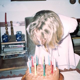 Dog blowing out birthday candles on cake.