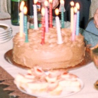 Family celebrating birthday with cake and drinks.
