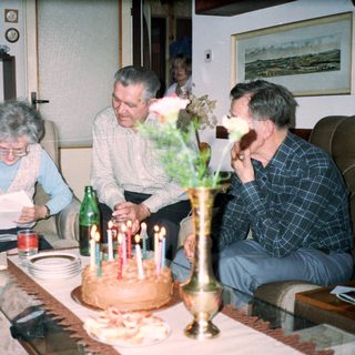 Family celebrating birthday with cake and drinks.