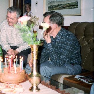 Family celebrating birthday with cake and drinks.
