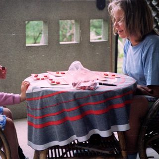 Two people playing cards outdoors on patio.