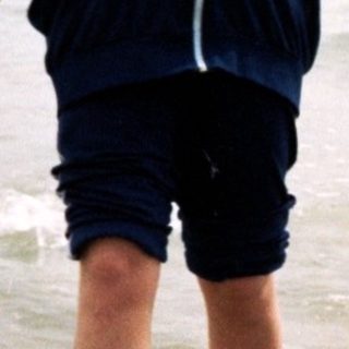 Two children holding hands walking in shallow ocean water.