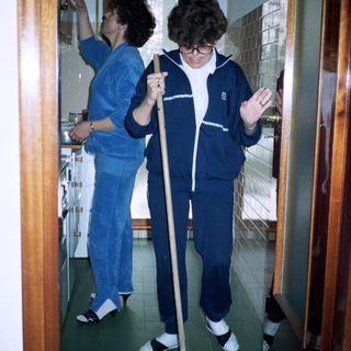 Two people cleaning with mops in uniform.