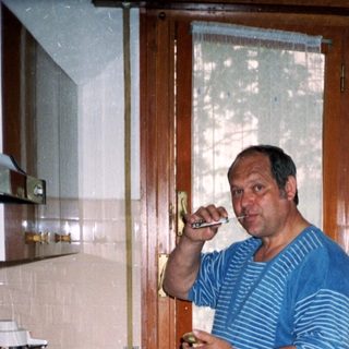 Man drinking coffee in retro kitchen by stove.