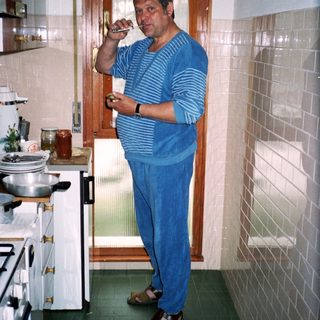 Man drinking coffee in retro kitchen by stove.