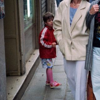 People walking on narrow urban street.