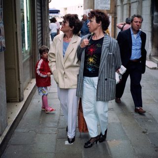 People walking on narrow urban street.