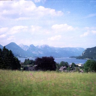 Scenic lake surrounded by mountains and green meadows.