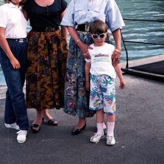 Family posing by a scenic lakefront near mountains.