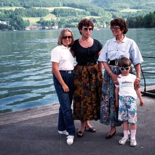 Family posing by a scenic lakefront near mountains.
