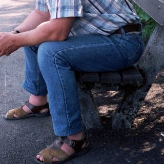 Man sitting alone on park bench near water.