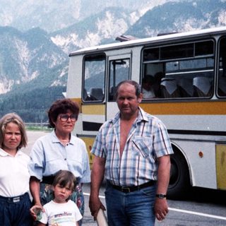 Family posing near mountainous area with bus.