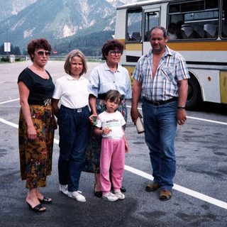 Family posing near mountainous area with bus.