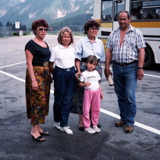 Family posing near mountainous area with bus.
