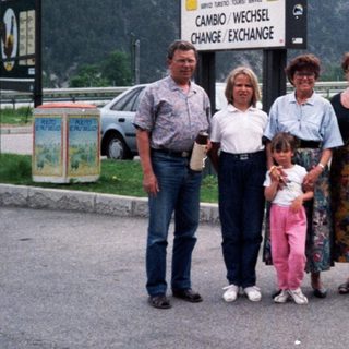 Family posing at EuroService currency exchange in mountainous area.