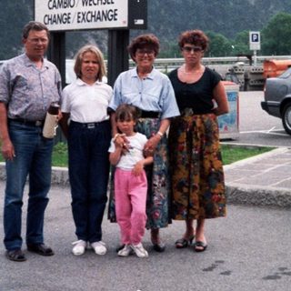 Family posing at EuroService currency exchange in mountainous area.